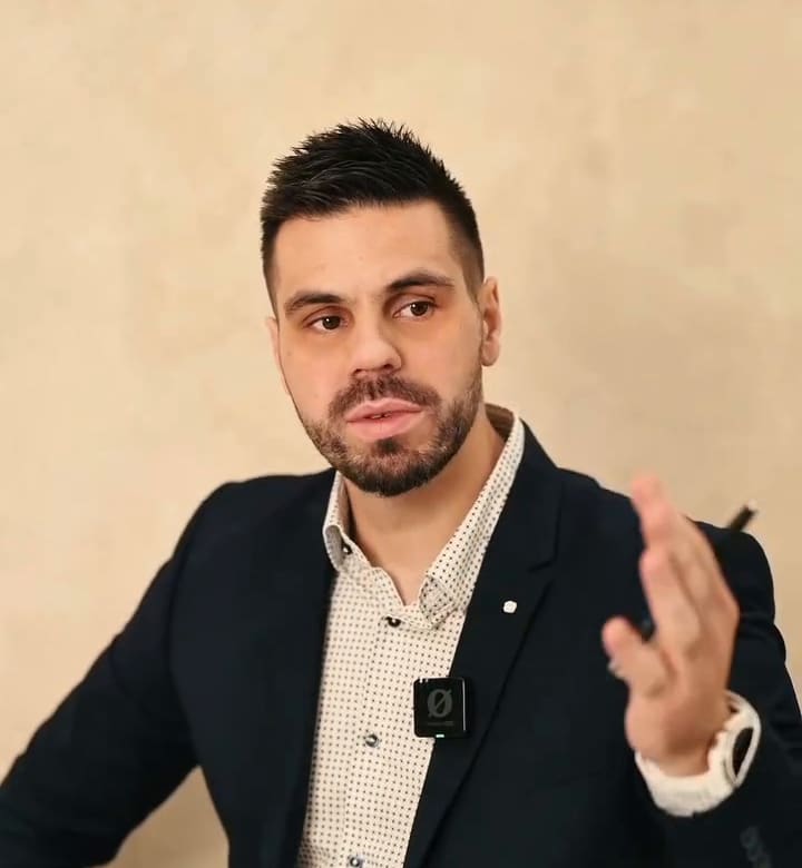 Dr Ivan Mladenović u tamnom sakou objašnjava pokretom ruke.